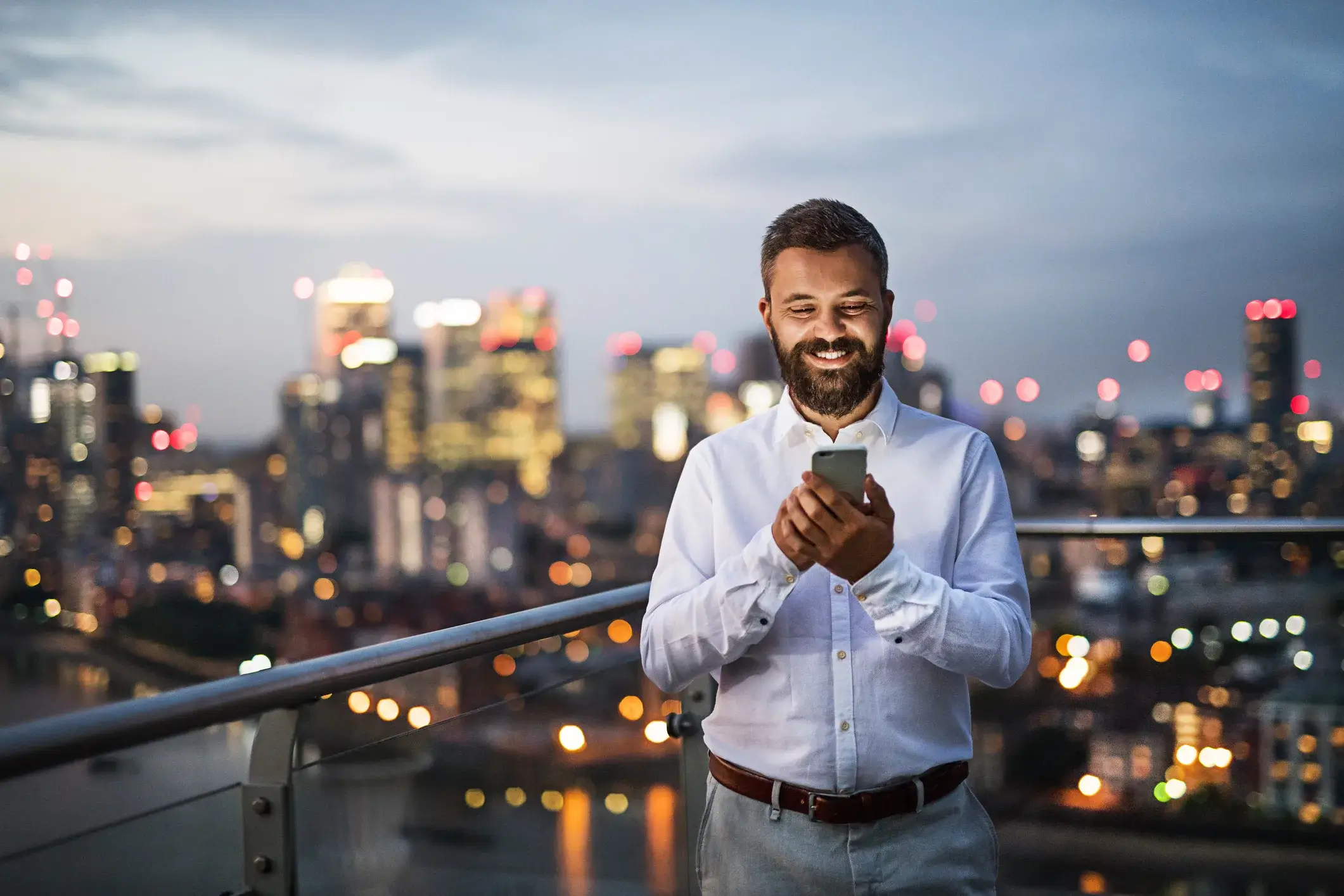 LinkedIn content strategy Calgary expert engages with his smartphone against a beautiful city skyline at dusk